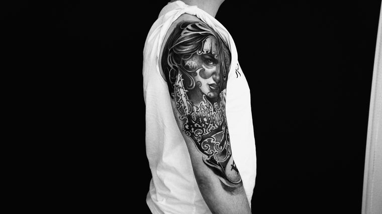 Portrait chicano en noir et gris, ornements fondus dans le fond de bras.