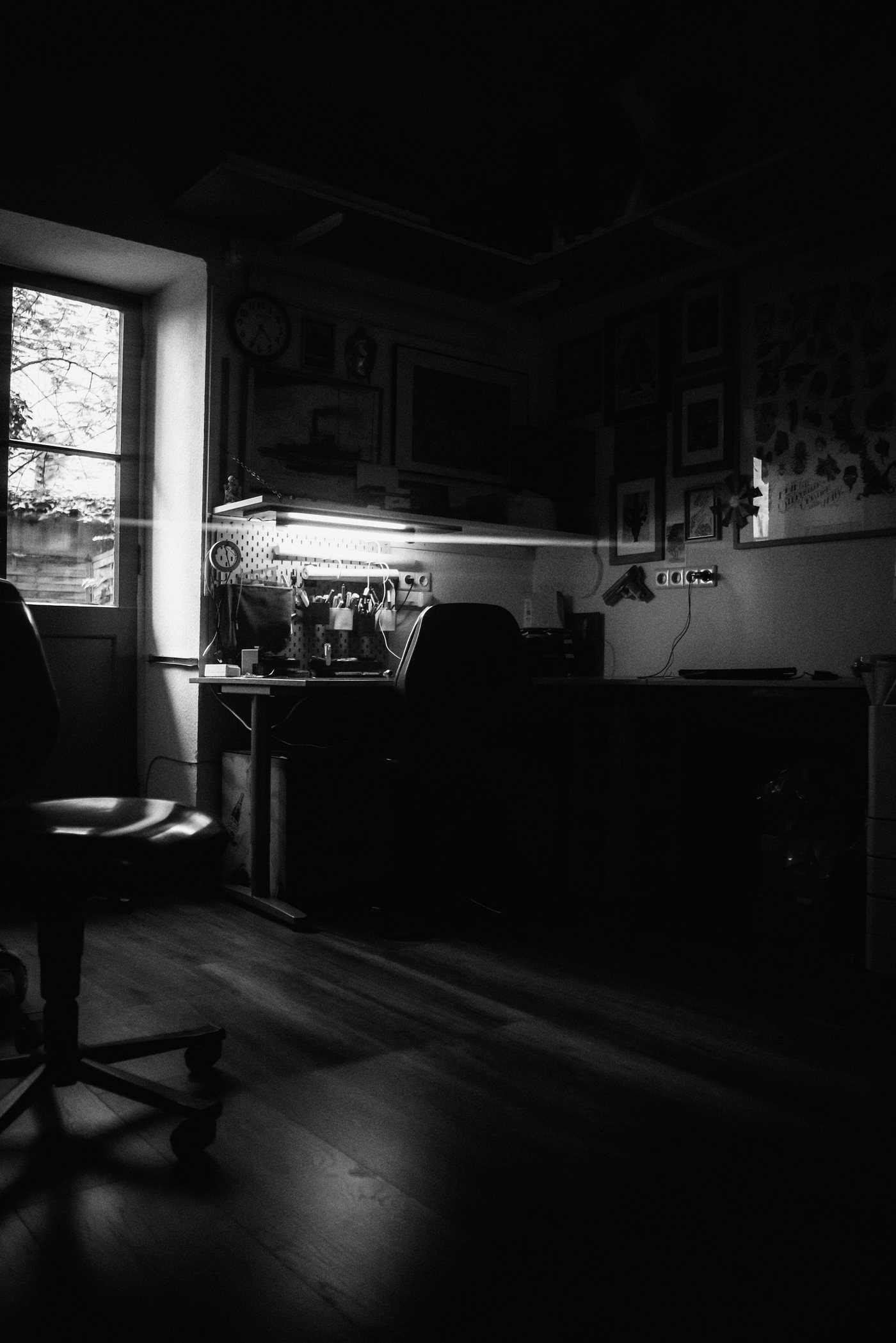 Intérieur du studio : bureau de dessin, lampe unique, murs sombres.